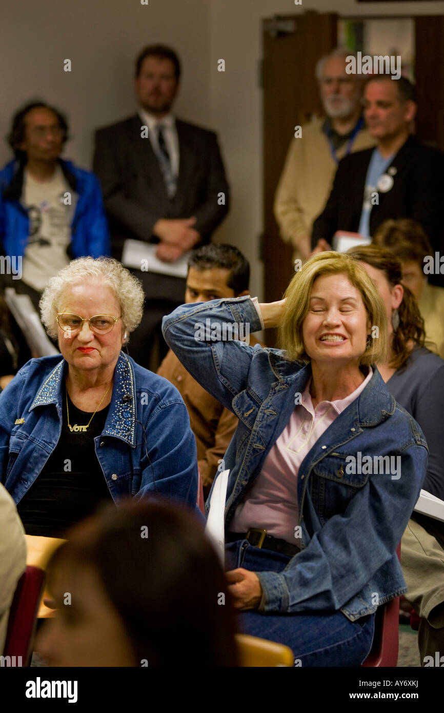 A woman reacts negatively to a speaker statement at a California political meeting Note range of audience expressions Stock Photo