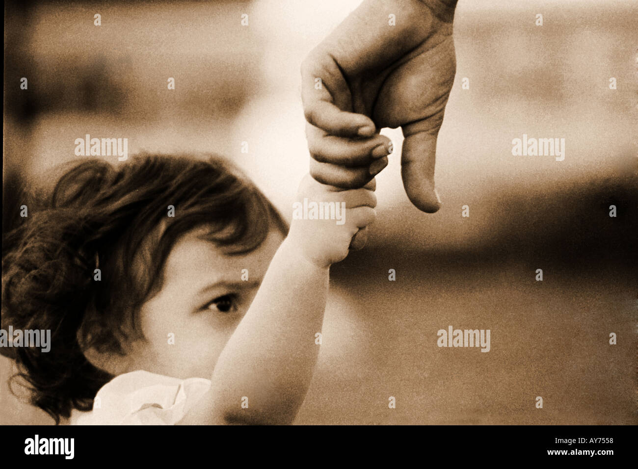 Small young girl child only one eye visible holding trusted fathers hands little finger Stock Photo