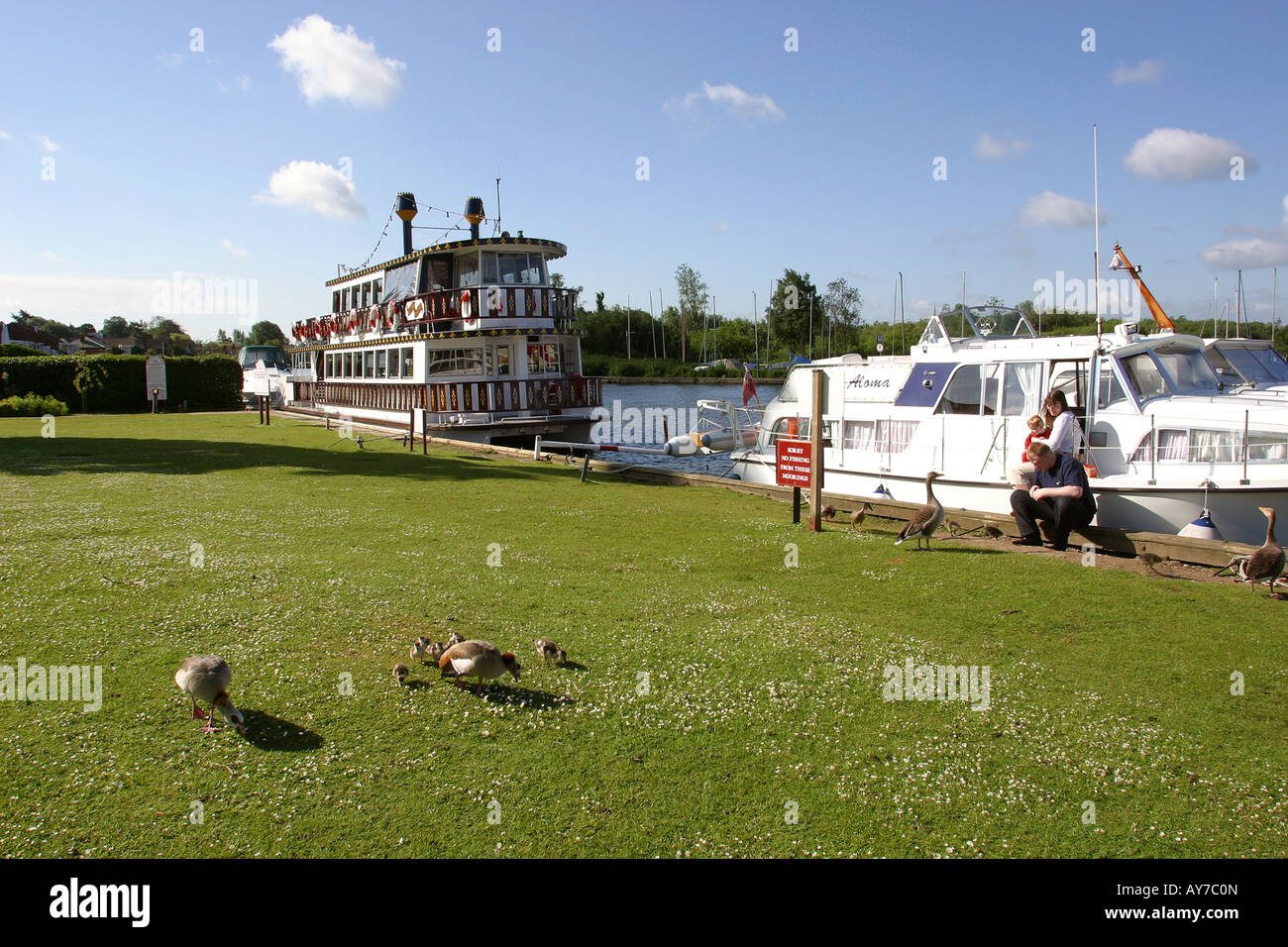 UK Norfolk Broads Horning Marina young holidaymaking family sat on steps of leisure craft Stock Photo