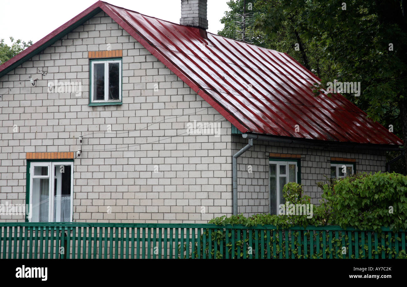 Two story house with bright red metal roof Green trim on 