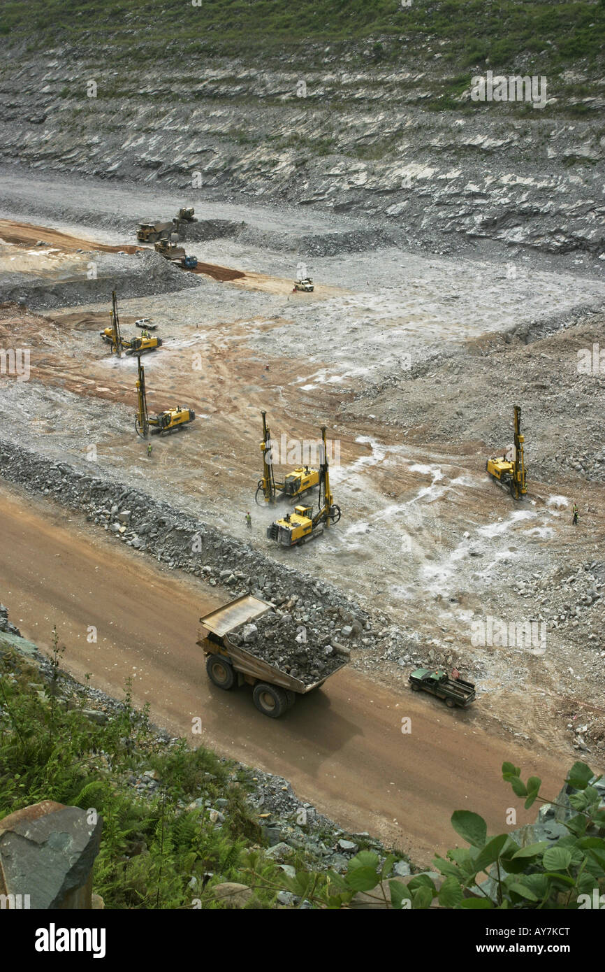 Overview of surface opencast gold mine, with drill rigs preparing for blasting and mining operations and hauler truck, Ghana Stock Photo