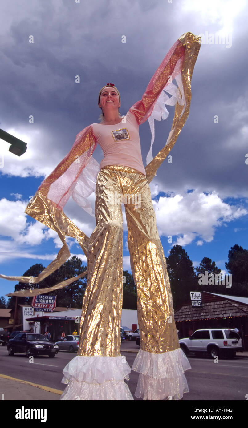 A tall teen girl waves to the crowd, while balancing on stilts, at the Street Players Festival in Ruidoso, New Mexico. Stock Photo