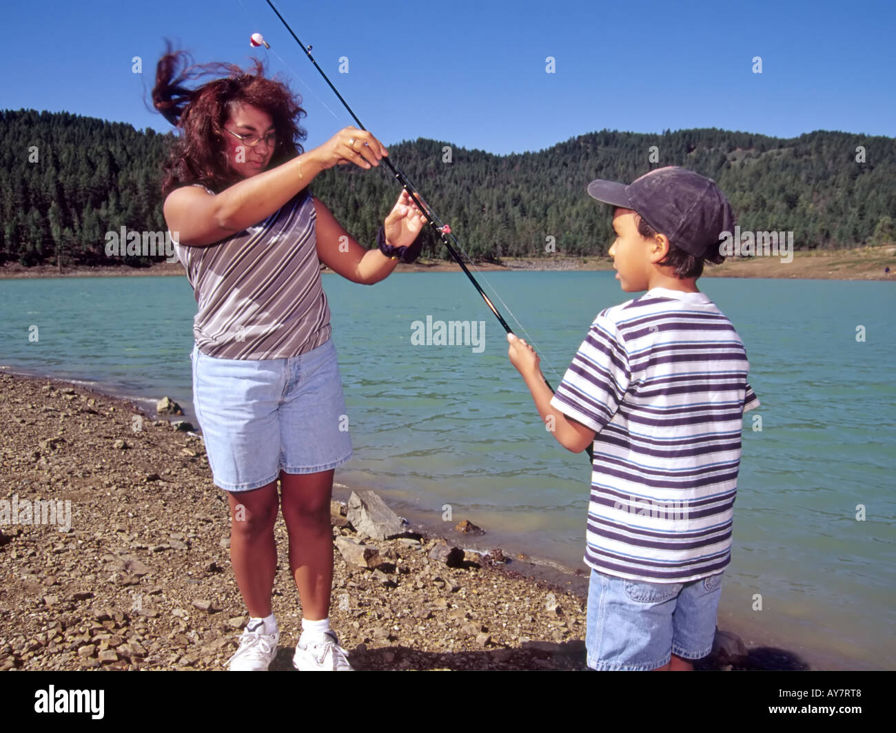 On a windy spring day, mom helps angler son untangle his tackle, during