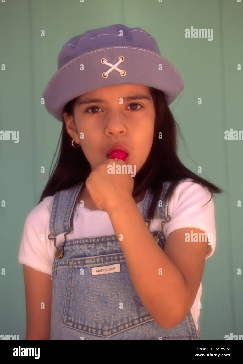 A portrait of a young Hispanic girl sucking on a lollipop, in Ruidoso, New Mexico. Stock Photo