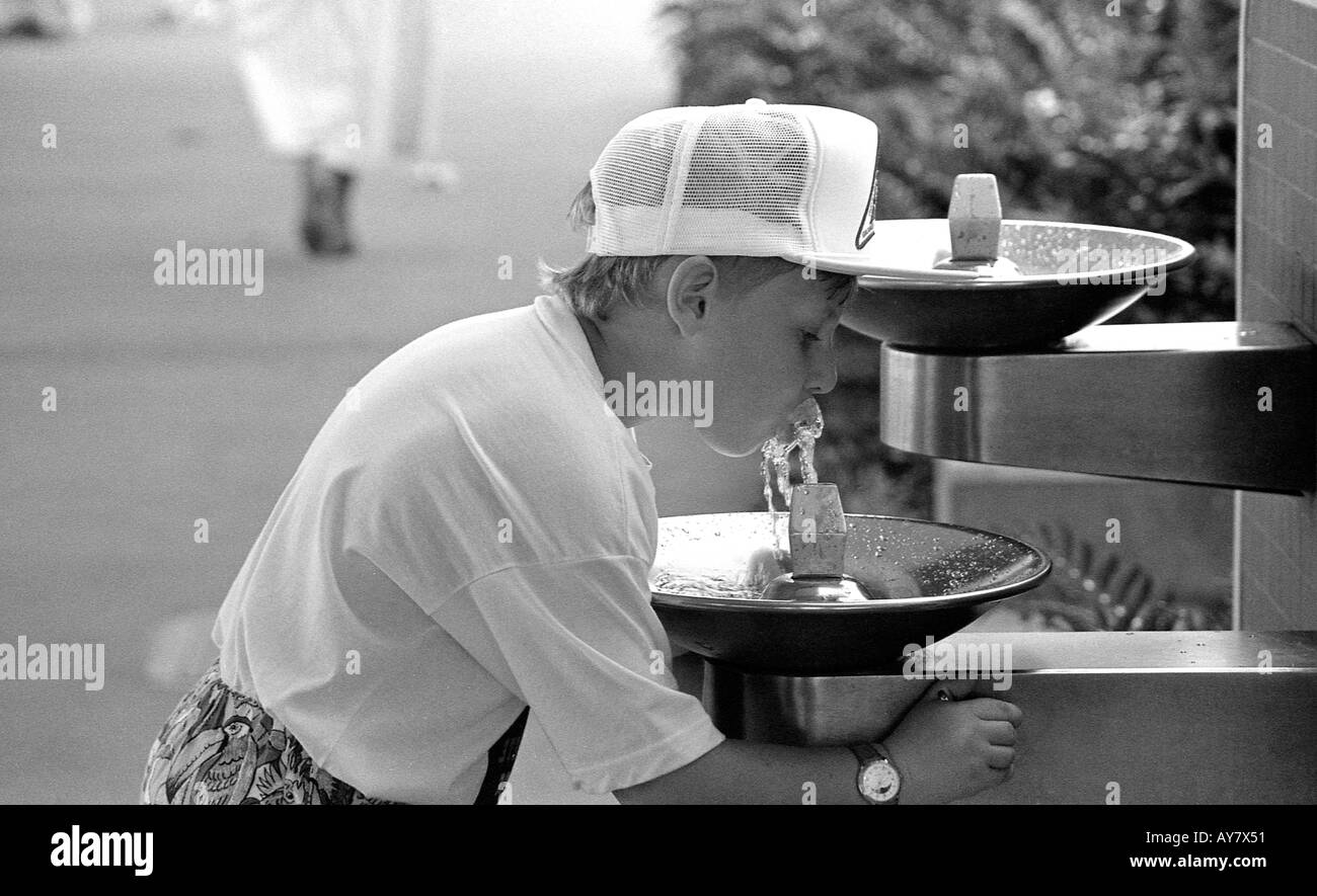 Young boy taking a drink of cold water from a public drinking fountain