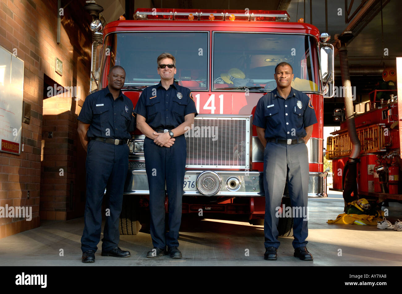 Three firefighters in front of fire truck Stock Photo