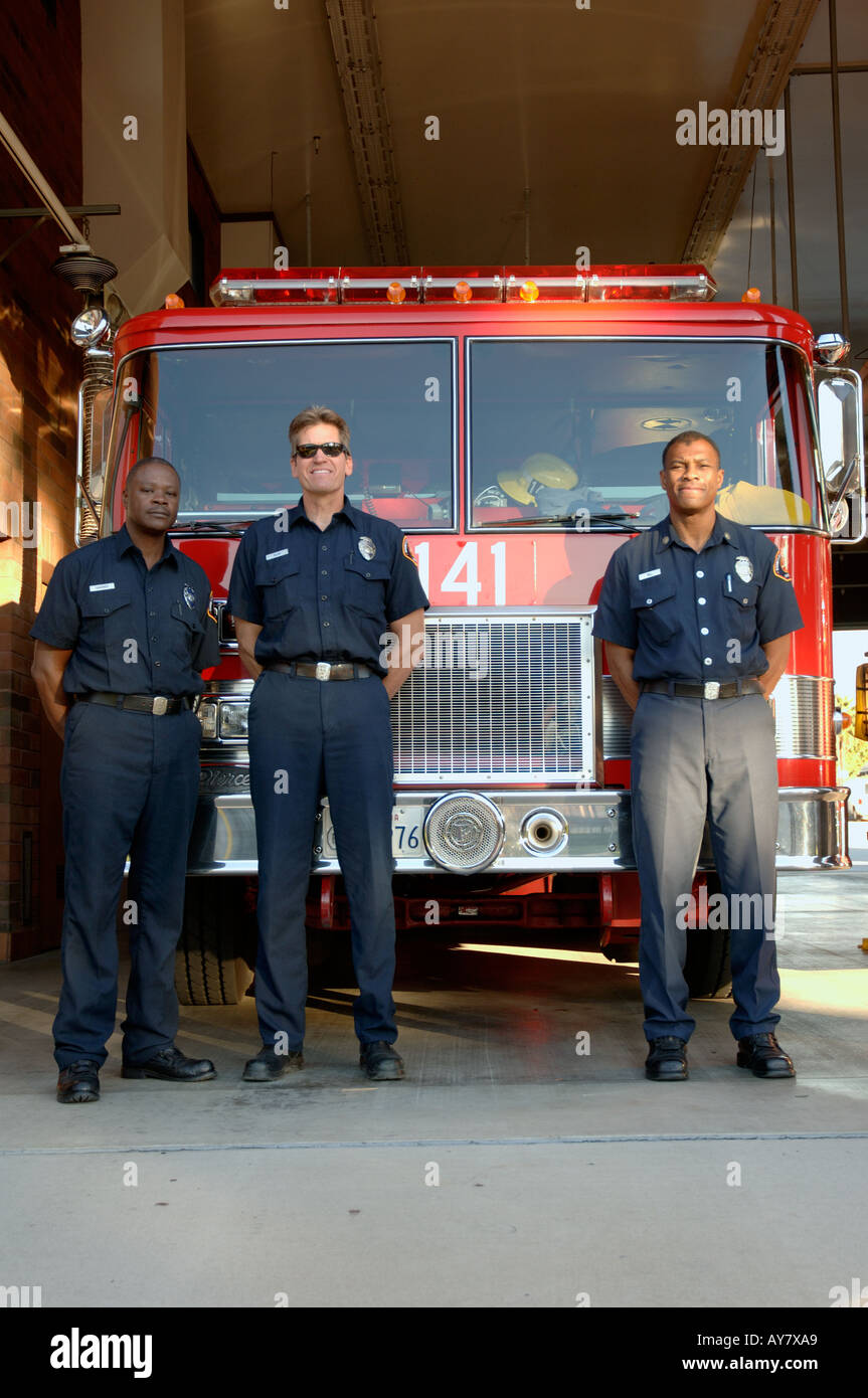 Three firefighters in front of fire truck Stock Photo