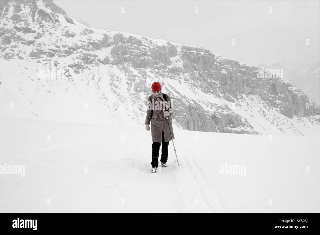 One Young Woman Crossing Mountain Top In Snowstorm Stock Photo