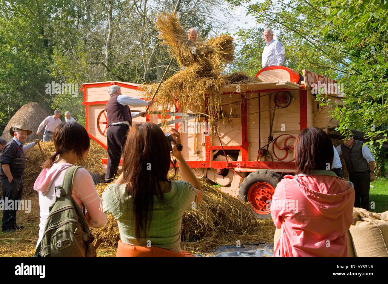 Bunratty Folk Park at Bunratty Castle, County Clare, Ireland. Tourists photograph traditional corn thresher demonstration Stock Photo