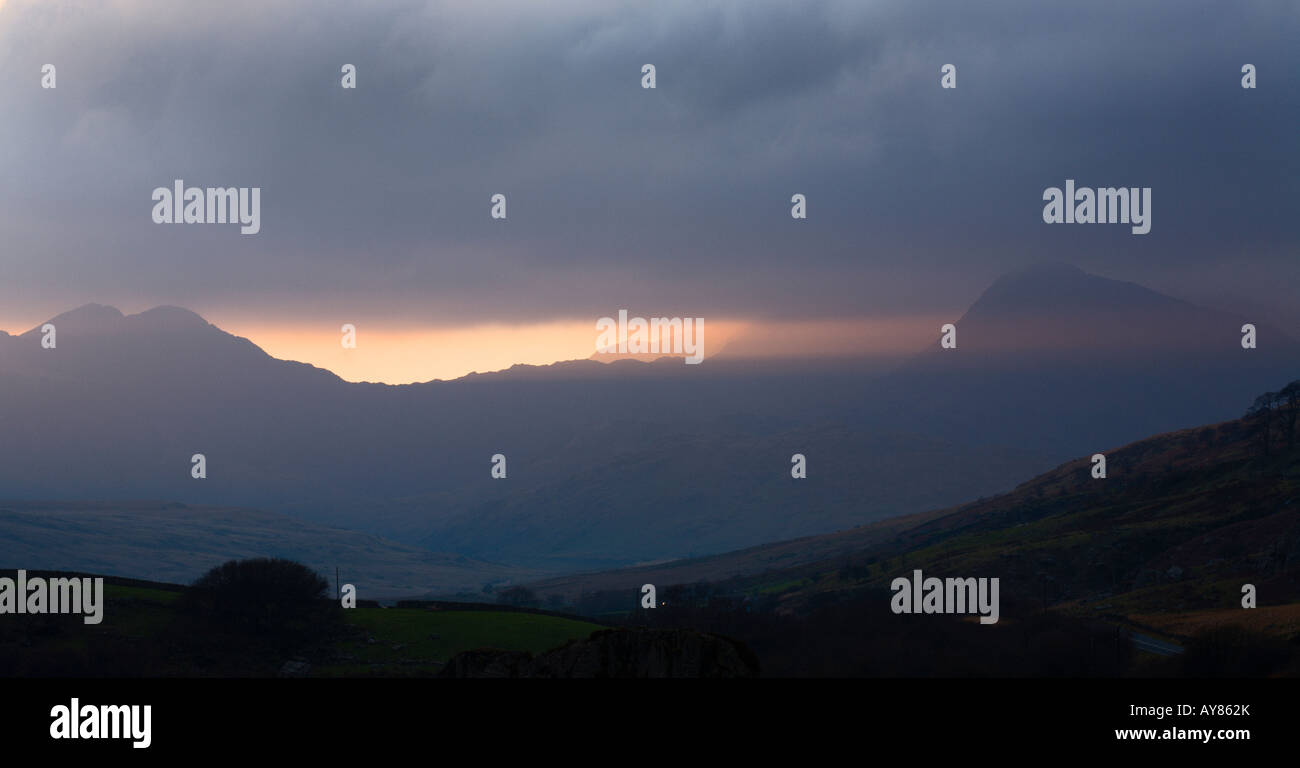 Sunlight bursting through the clouds over Mt Snowdon at sunset Snowdonia Wales UK Stock Photo
