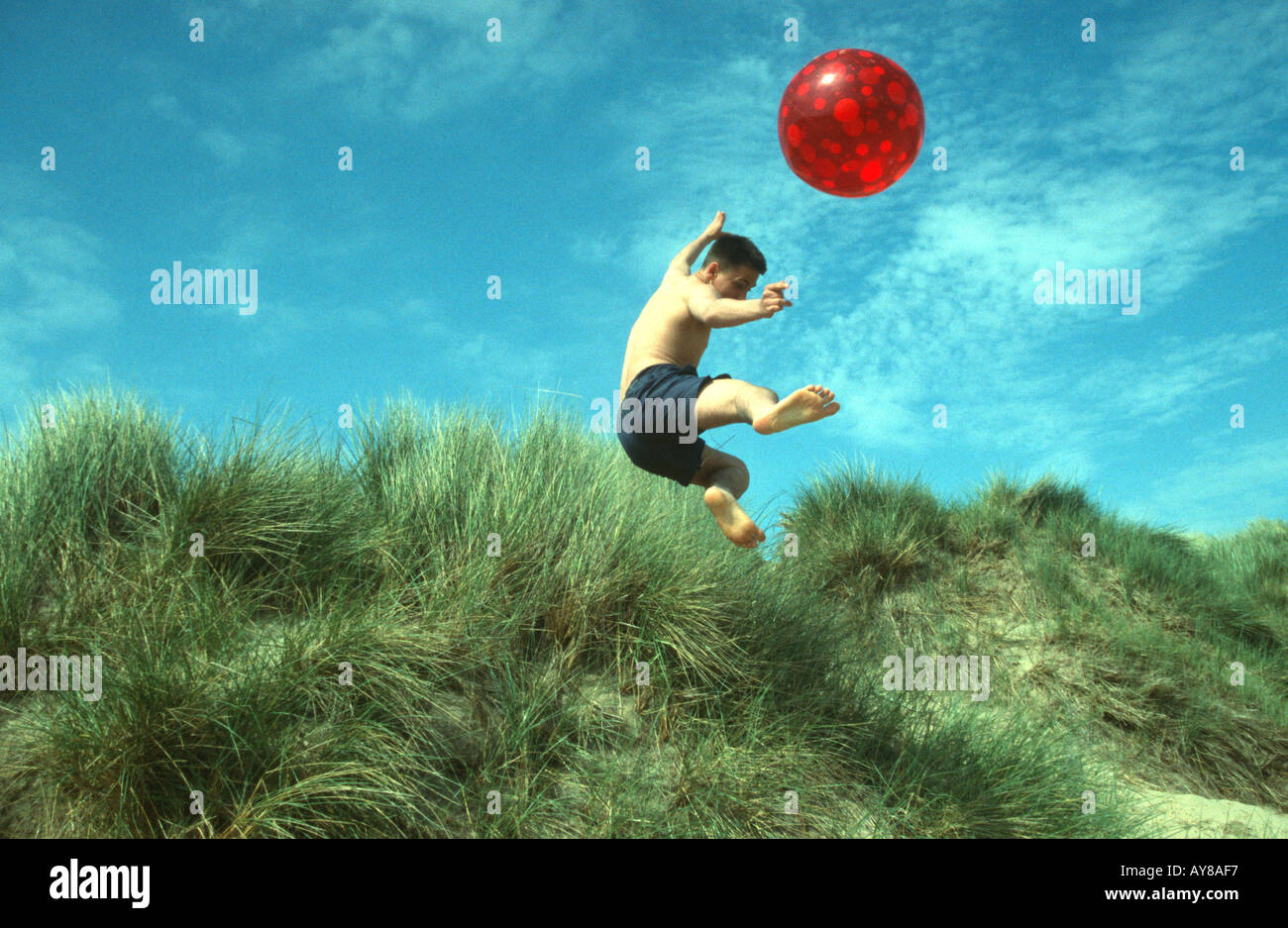 Boy jumping sand dunes Camber Sands beach Sussex England South Coast UK