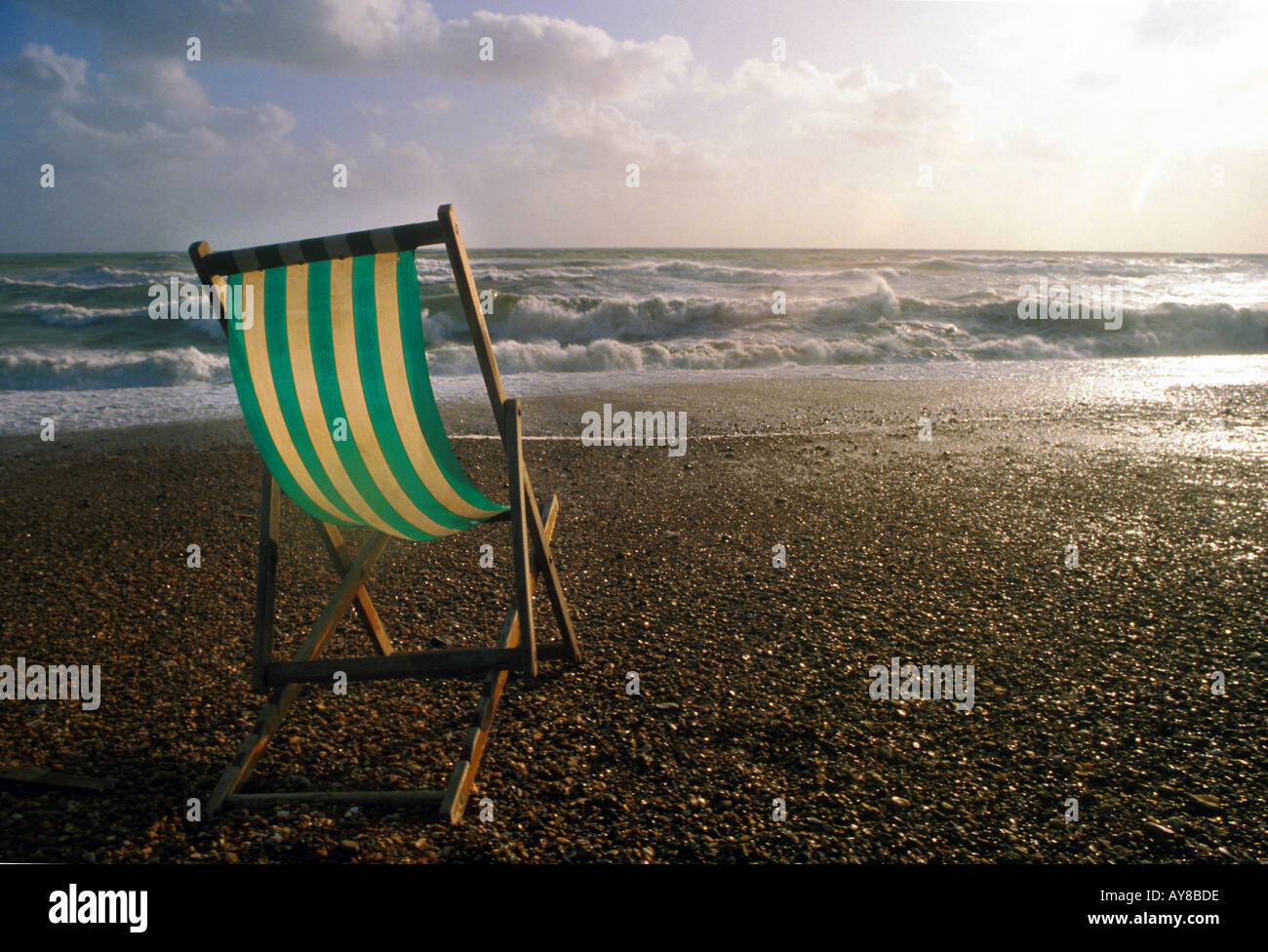 Deckchair blown by the wind with stormy sea in background Brighton beach East Sussex England UK Stock Photo