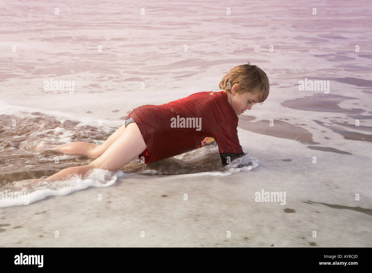 young boy running down the beach in his tee shirt and pants Stock Photo Alamy