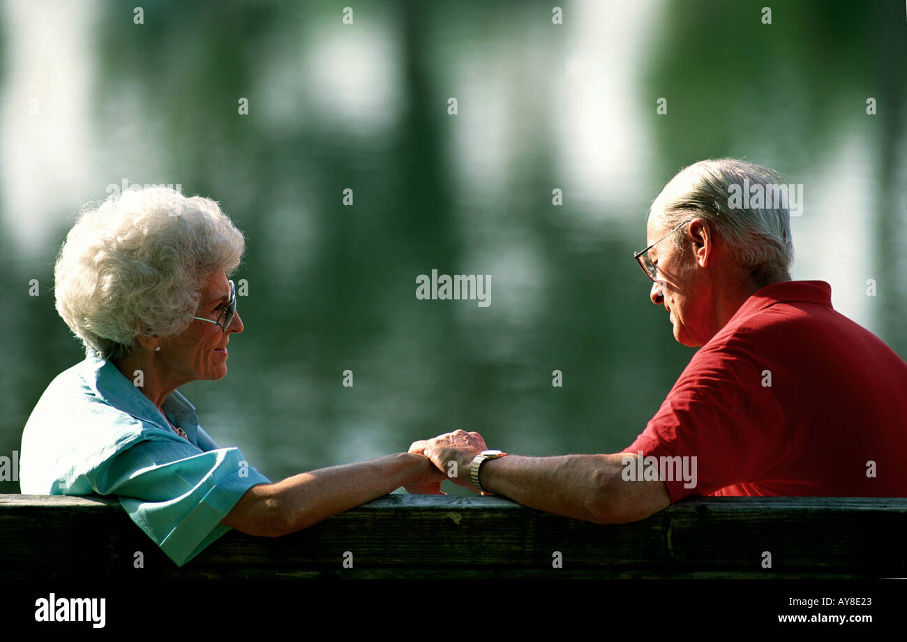 Elderly couple hold hands in park Stock Photo - Alamy