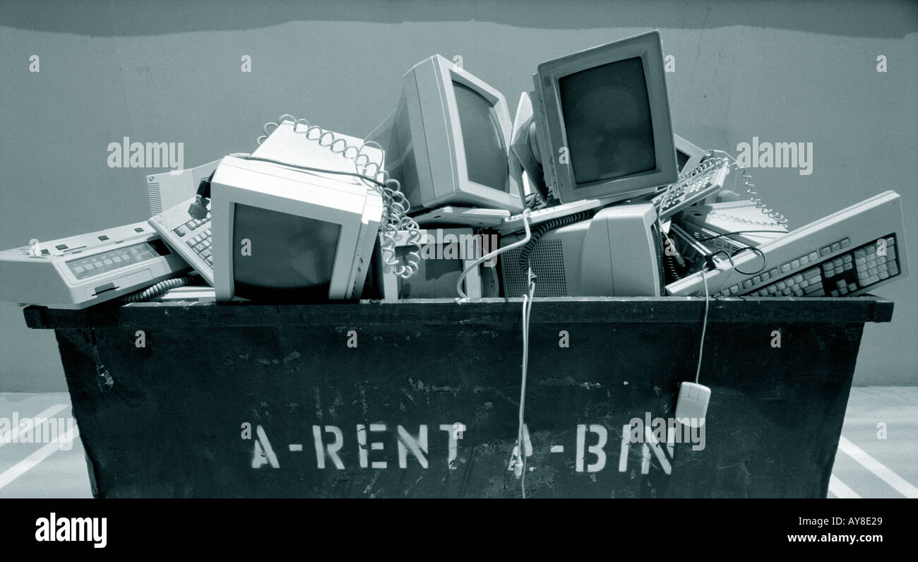 Outdated computers and monitors in trash bin outside highrise office building Stock Photo