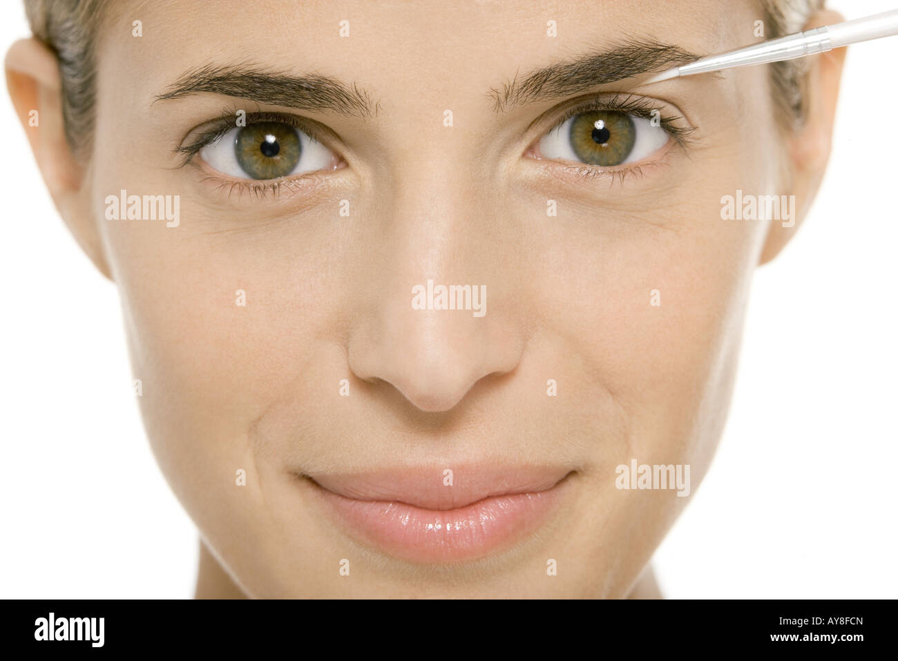 Woman applying make-up, smiling at camera Stock Photo