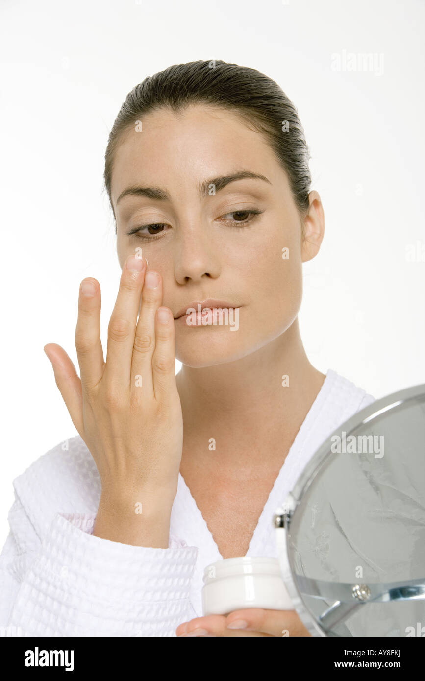 Woman looking into mirror, applying face cream Stock Photo