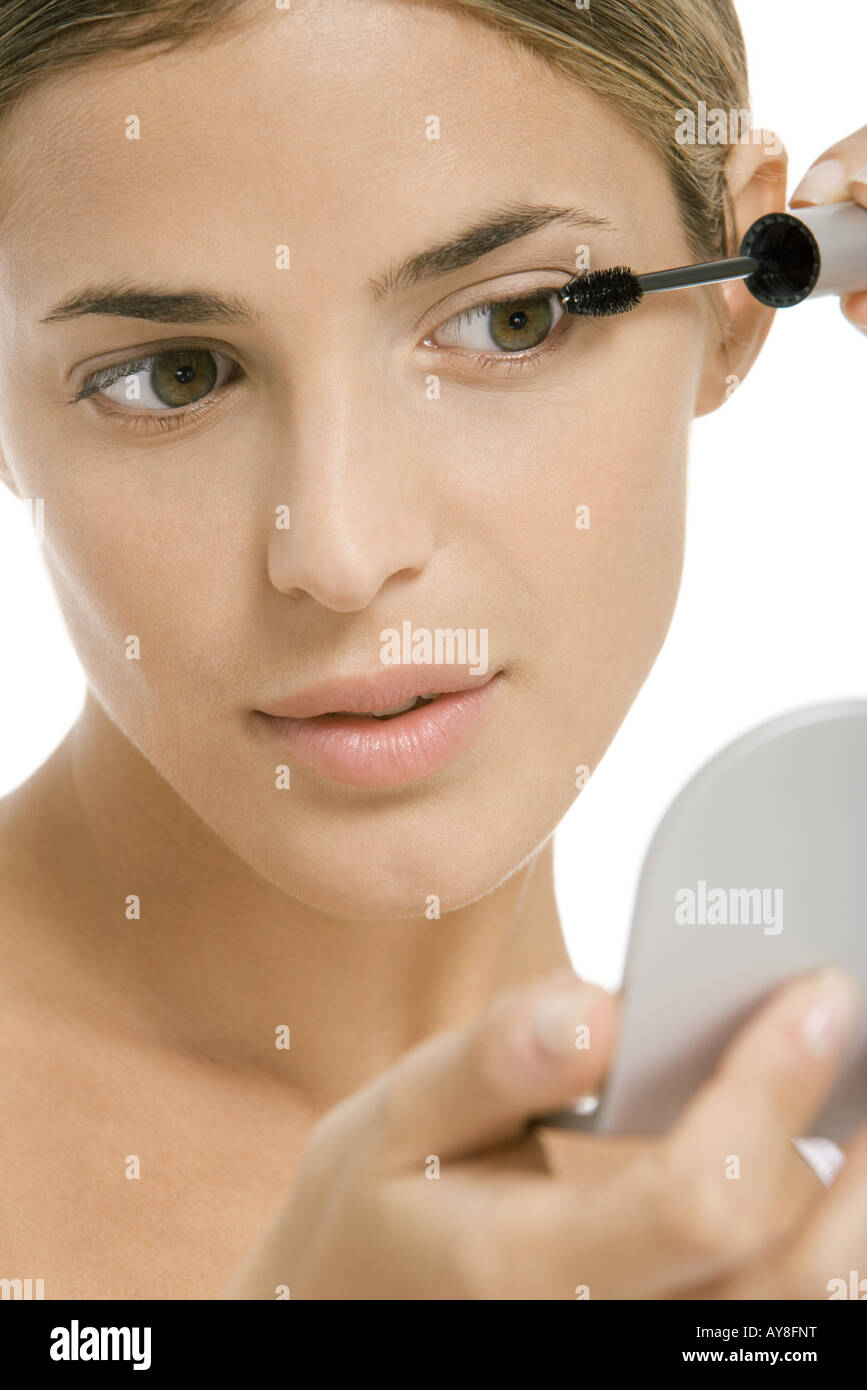 Woman putting on mascara, looking in hand mirror, close-up Stock Photo