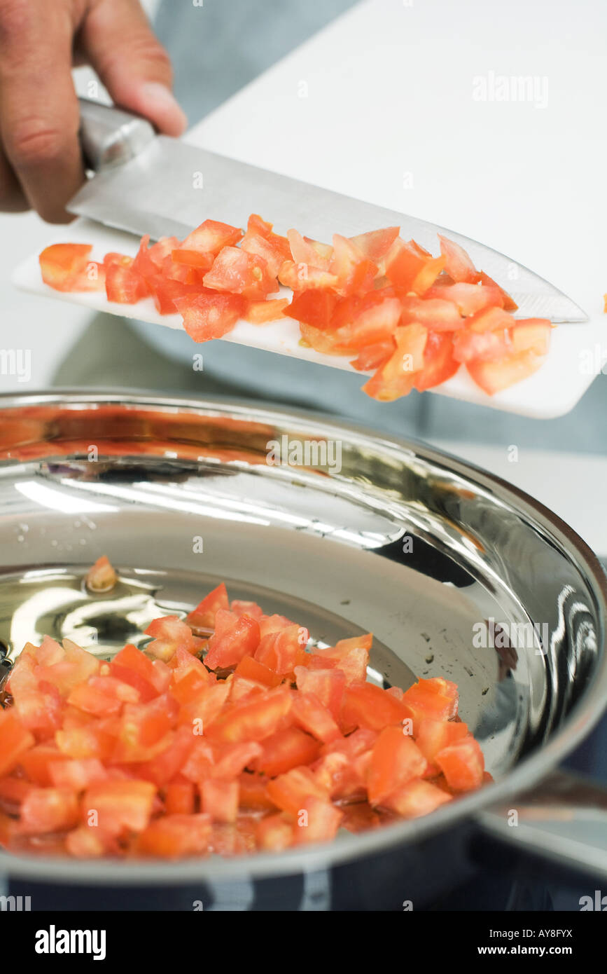 Man scraping diced tomatoes into saucepan with knife, cropped view Stock Photo Alamy