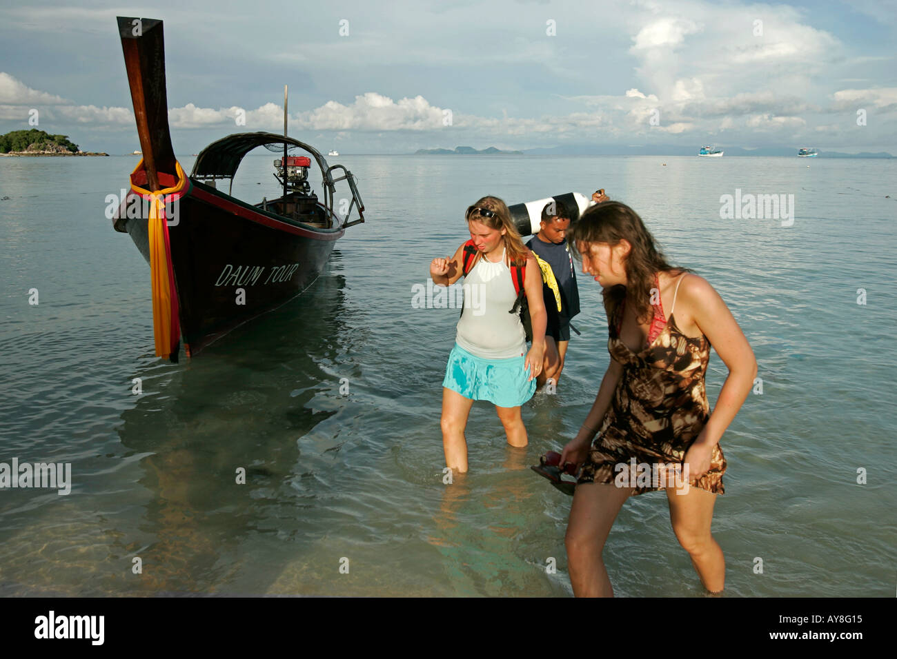 Two young women wade ashore from traditional longtail dive boat Ko Lipe island Thailand Stock Photo