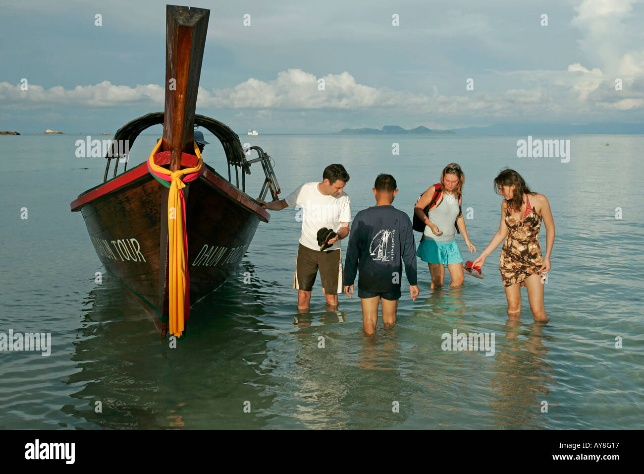 Young people wade ashore after traditional longtail boat excursion Ko Lipe island Thailand Stock Photo