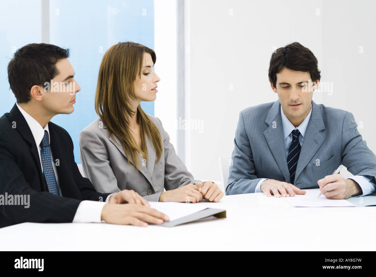 Business associates in meeting, man signing document while others watch Stock Photo