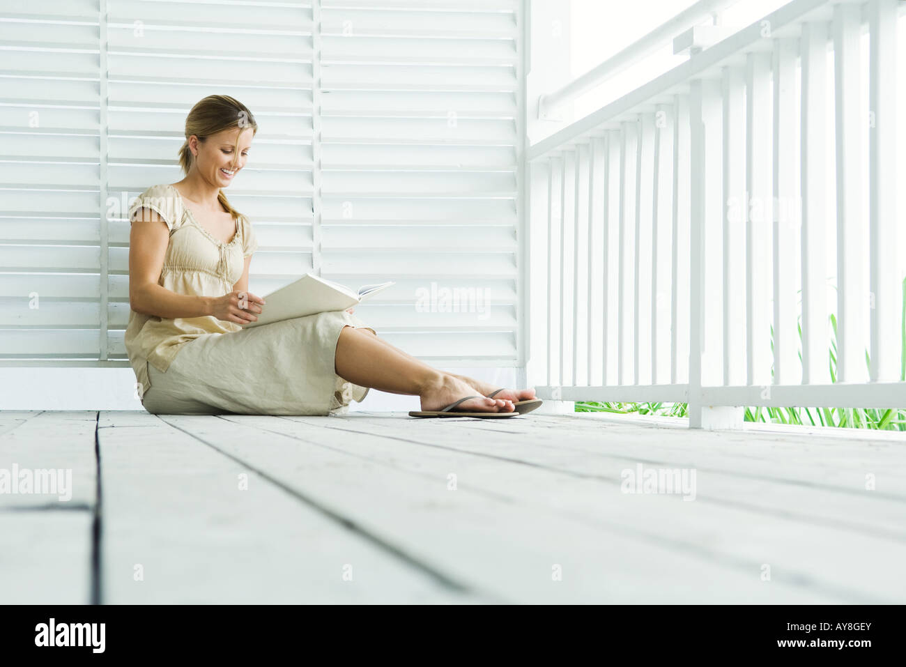 Woman sitting on porch reading book, low angle view Stock Photo - Alamy