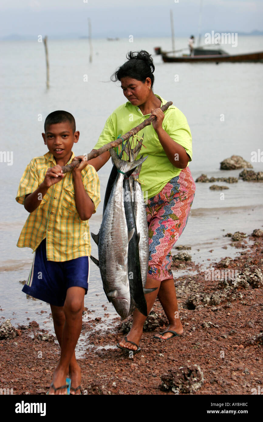 Woman and boy carry fresh Spanish Mackerel on pole Ban Batu fishing ...
