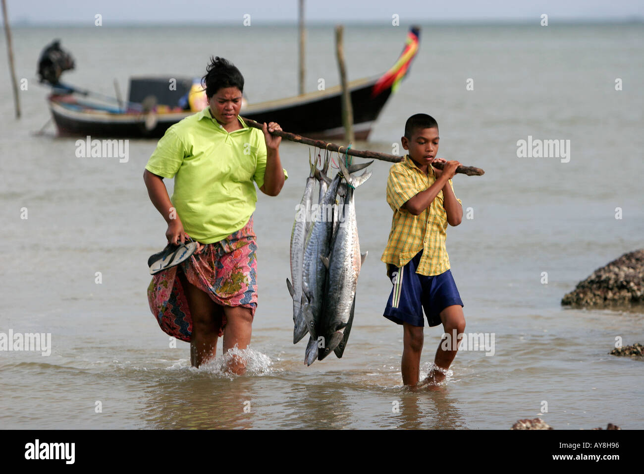 Woman and boy carry fresh Spanish Mackerel on pole Ban Batu fishing ...