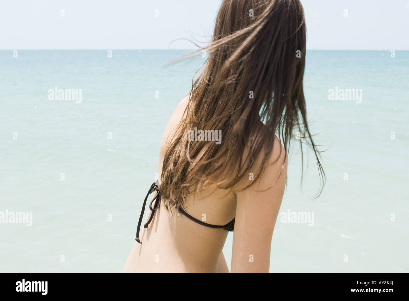 Young woman in bikini at the beach, looking at horizon, side view Stock Photo