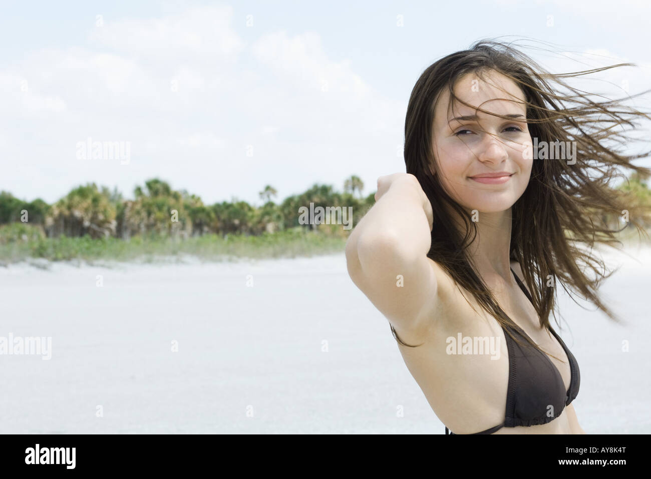 Young woman with hair tousled by wind, smiling at camera Stock Photo