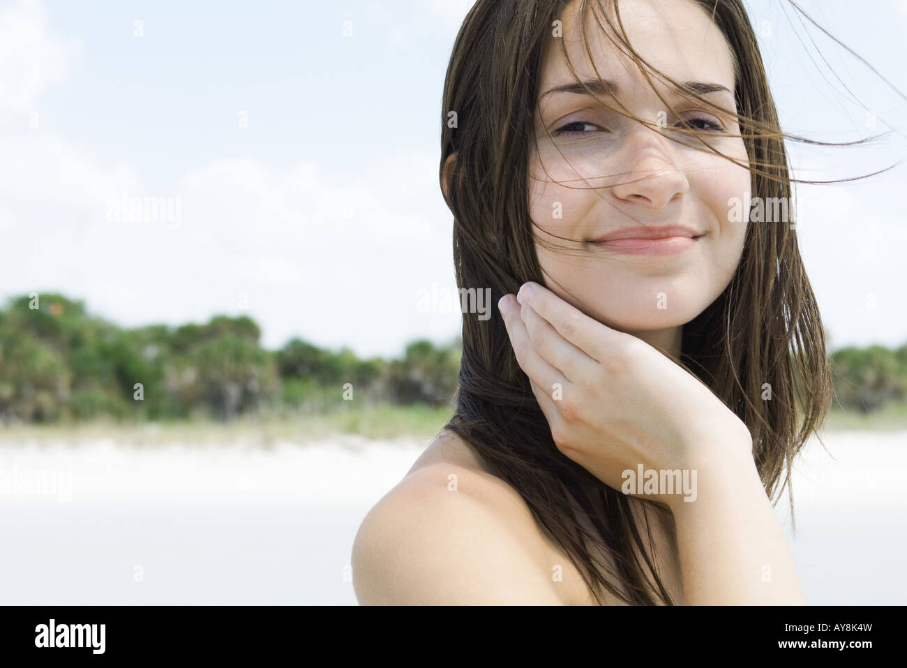 Young woman with hair tousled by wind, smiling at camera, close-up Stock Photo
