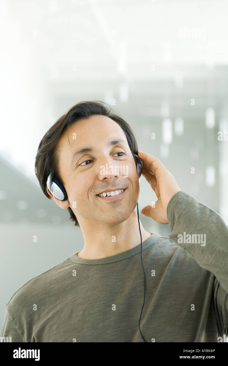 Man listening to headphones, looking away, smiling Stock Photo