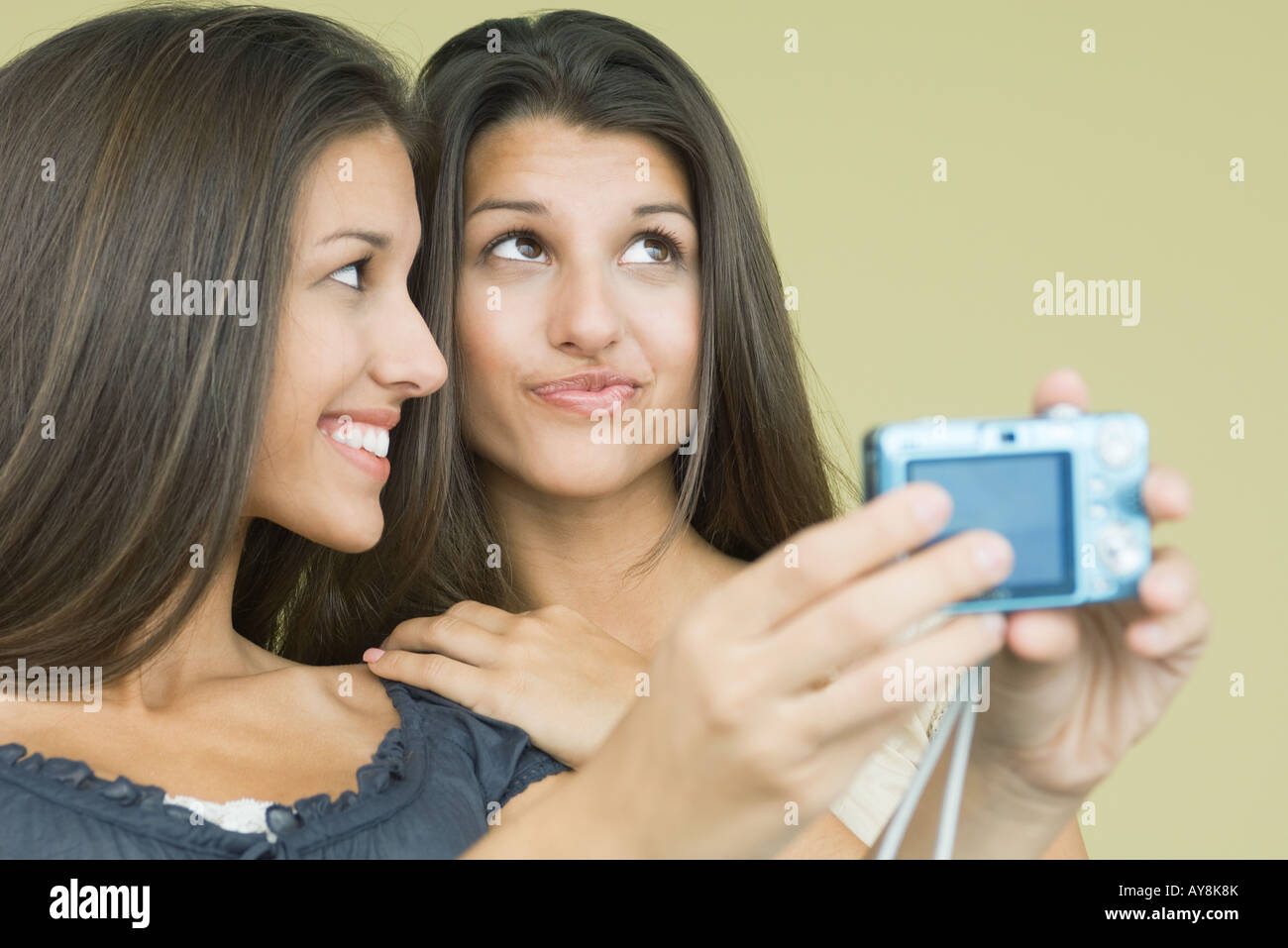Teenage girl photographing self and twin sister with digital camera, both  looking away, close-up Stock Photo - Alamy