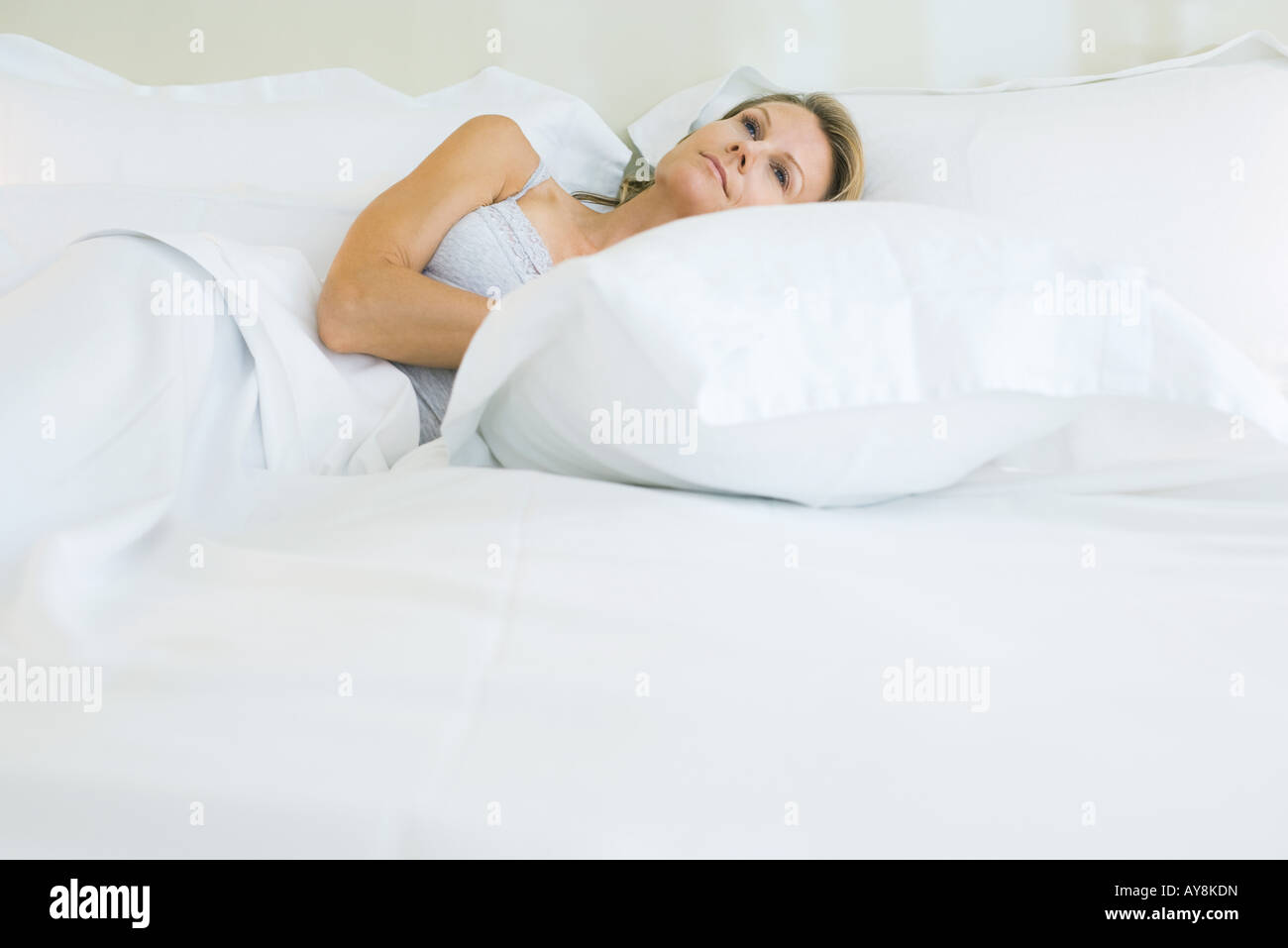 Woman lying with head on pillow, looking up, smiling Stock Photo - Alamy
