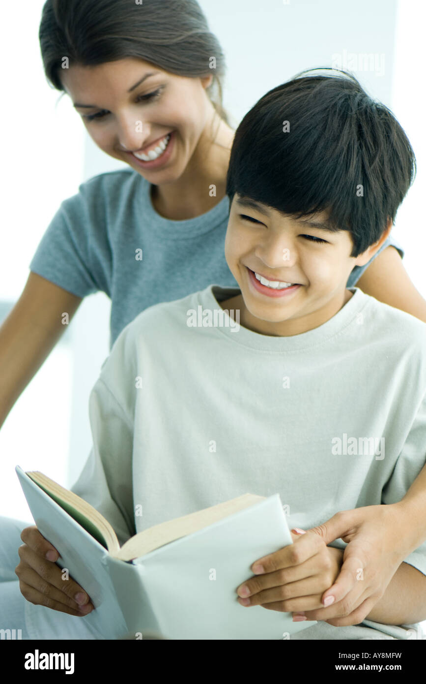 Teenage girl helping boy read book Stock Photo