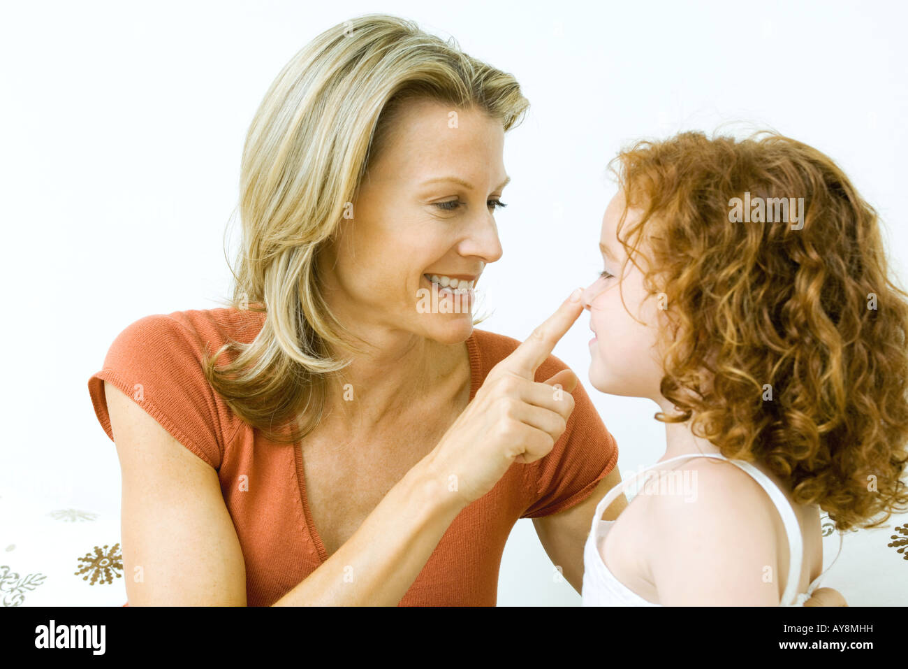 Woman touching daughter's nose, both smiling Stock Photo