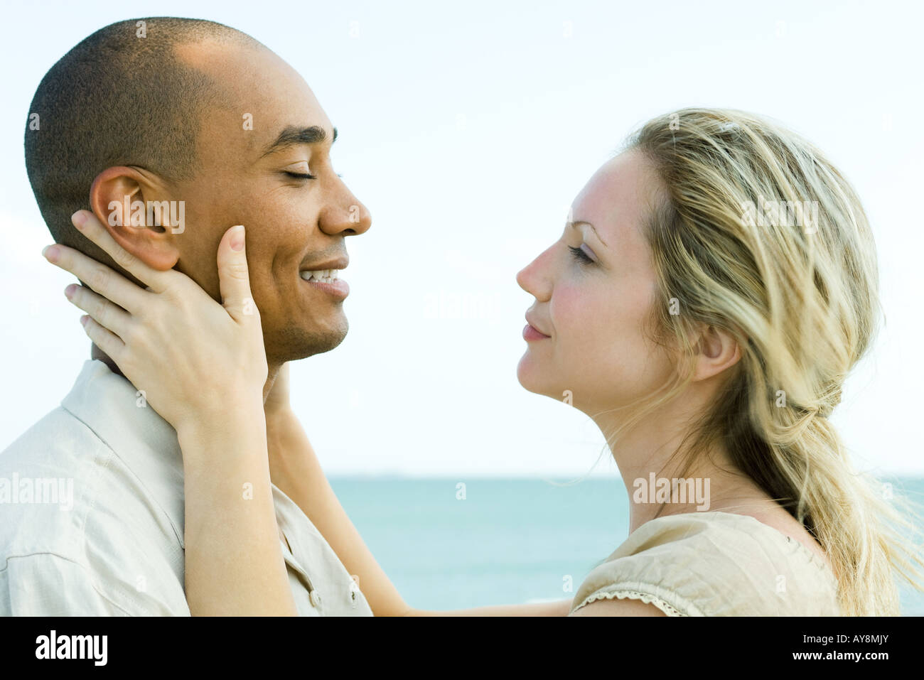 Couple face to face, woman holding man's neck, side view Stock Photo