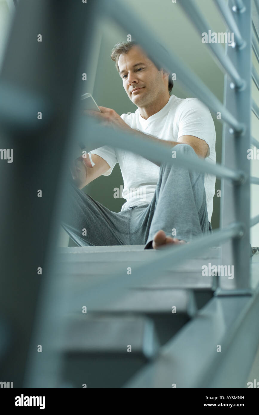 Man sitting on stairs reading book, low angle view Stock Photo