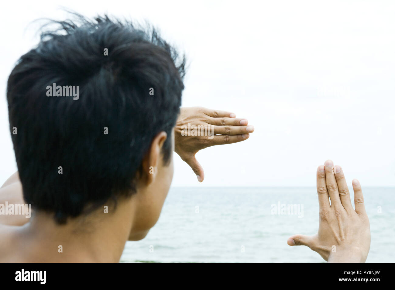 Man by the sea, looking at view through finger frame Stock Photo