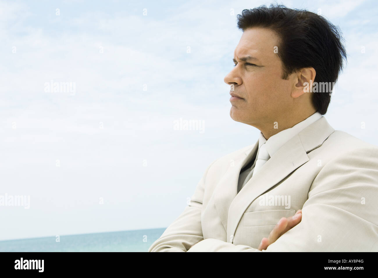 Businessman crossing arms, looking at distance, sea in background Stock Photo