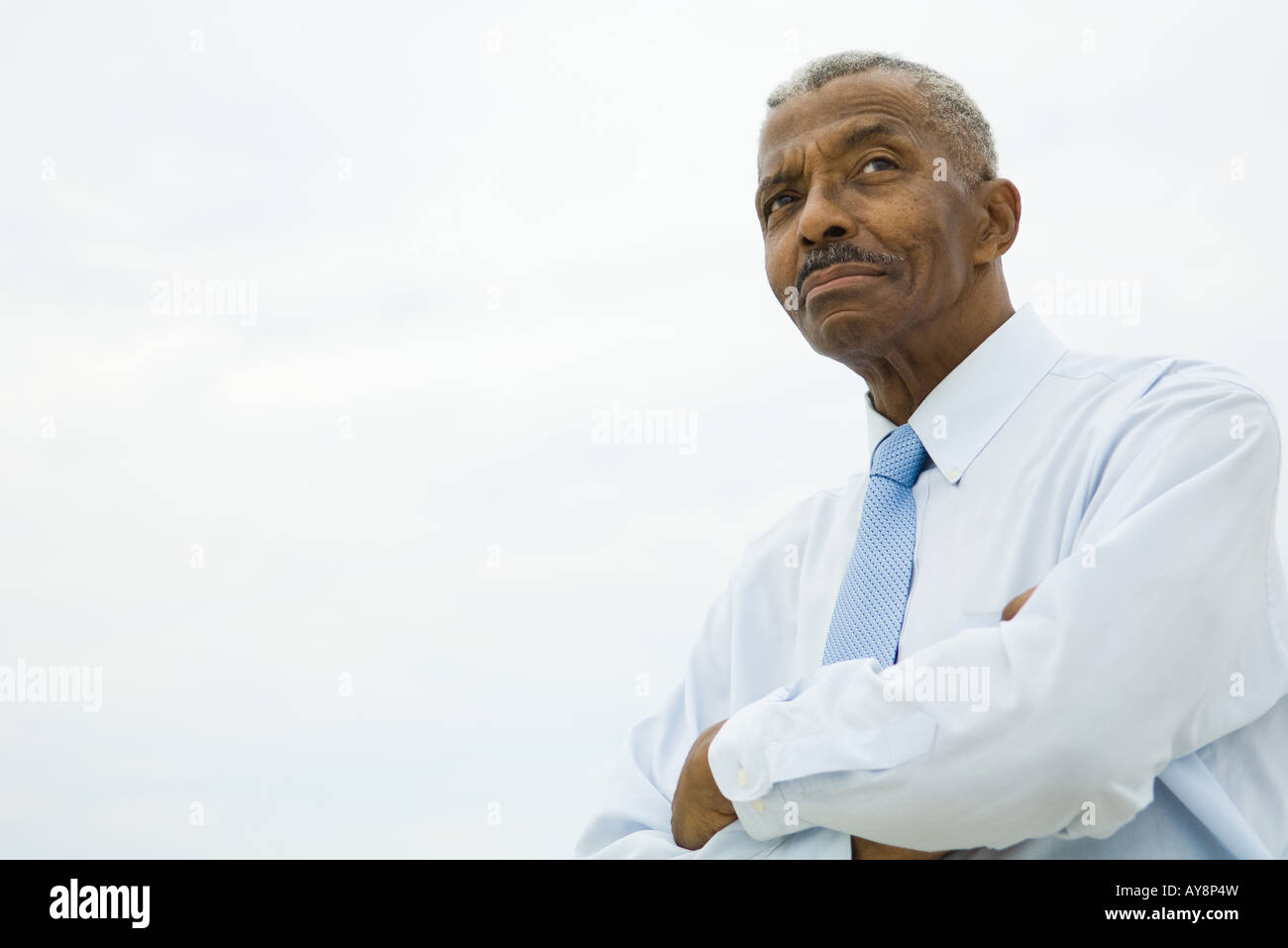 Businessman with arms folded, looking away, low angle view Stock Photo ...