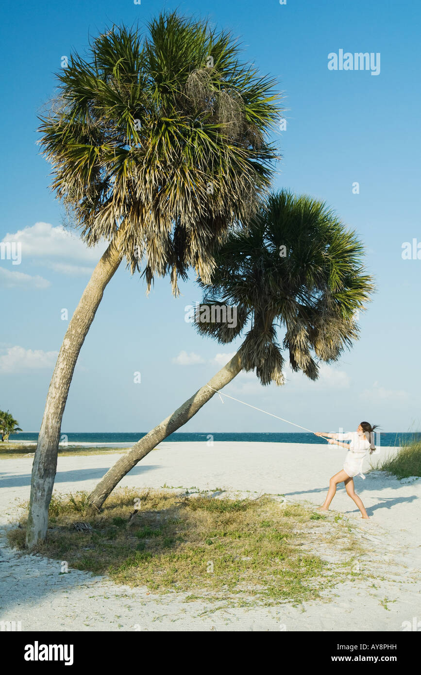 Female at the beach, pulling rope tied to palm tree, mid-distance Stock ...