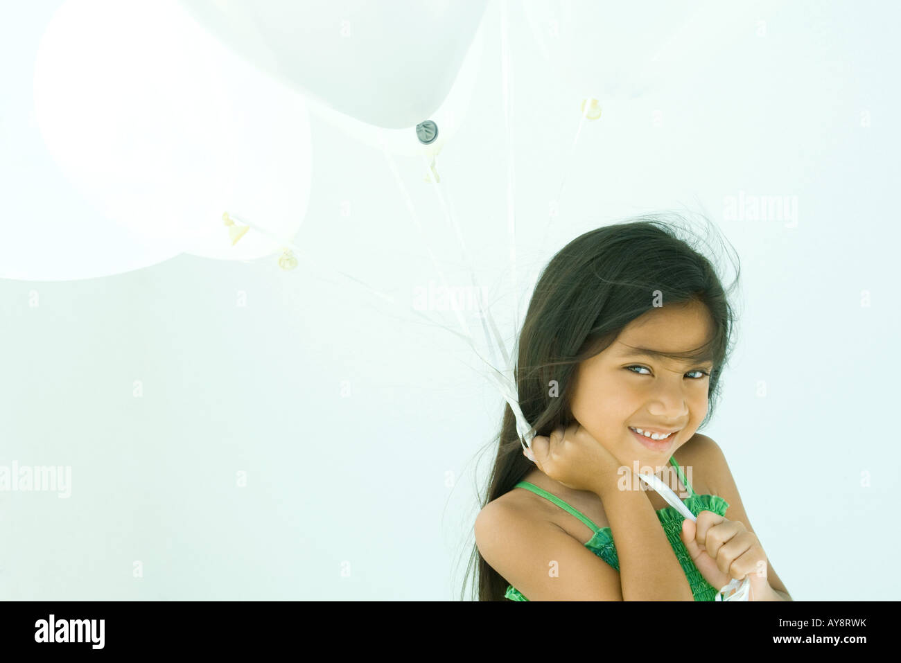 Little girl holding balloons, smiling at camera, portrait Stock Photo