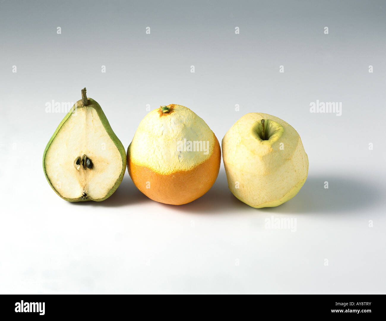 Pear, orange, and apple in a row, all partially peeled Stock Photo