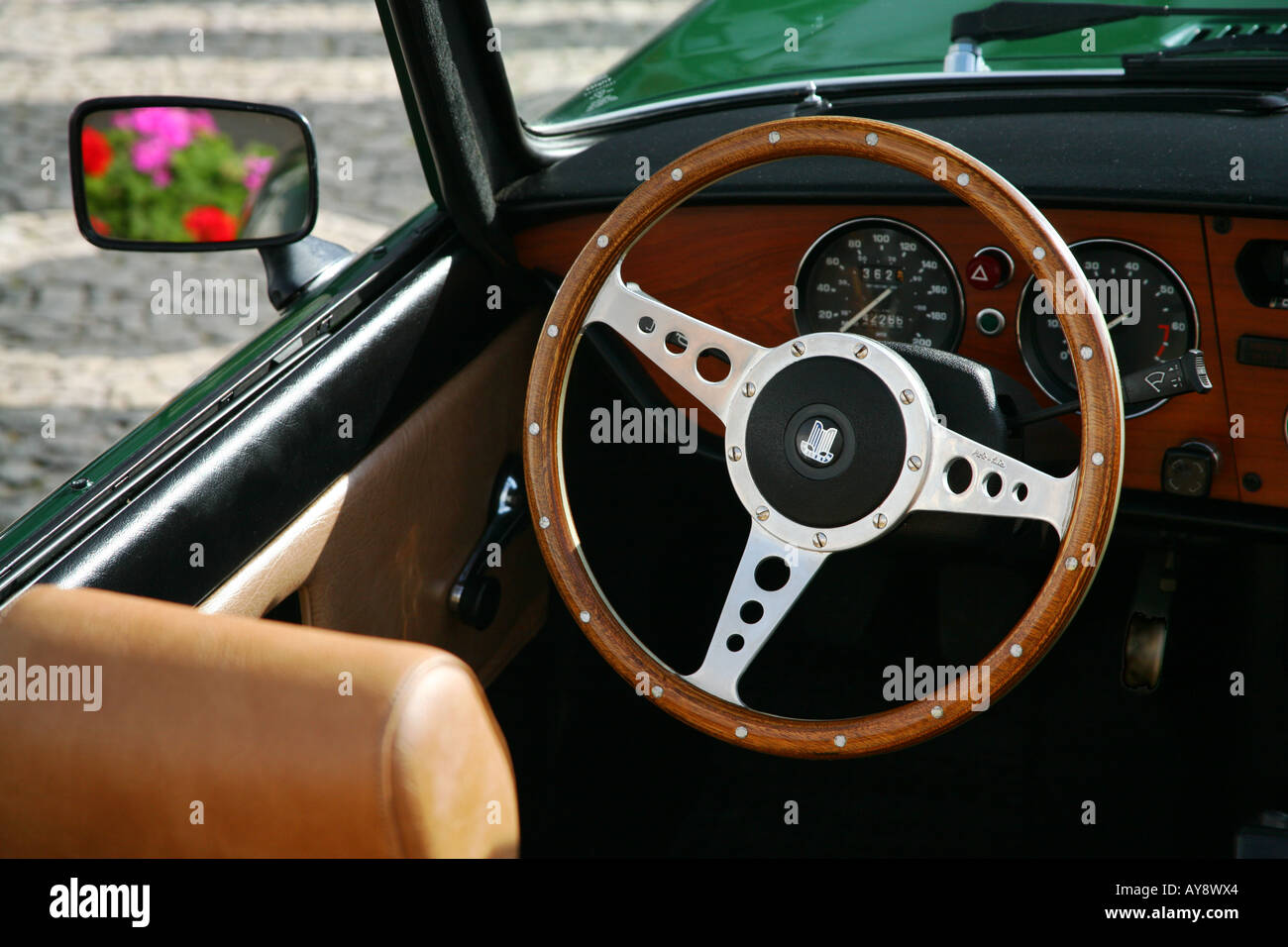 Interior view of a classic car (Triumph Spitfire 500), with flowers showing in the side mirror. Stock Photo