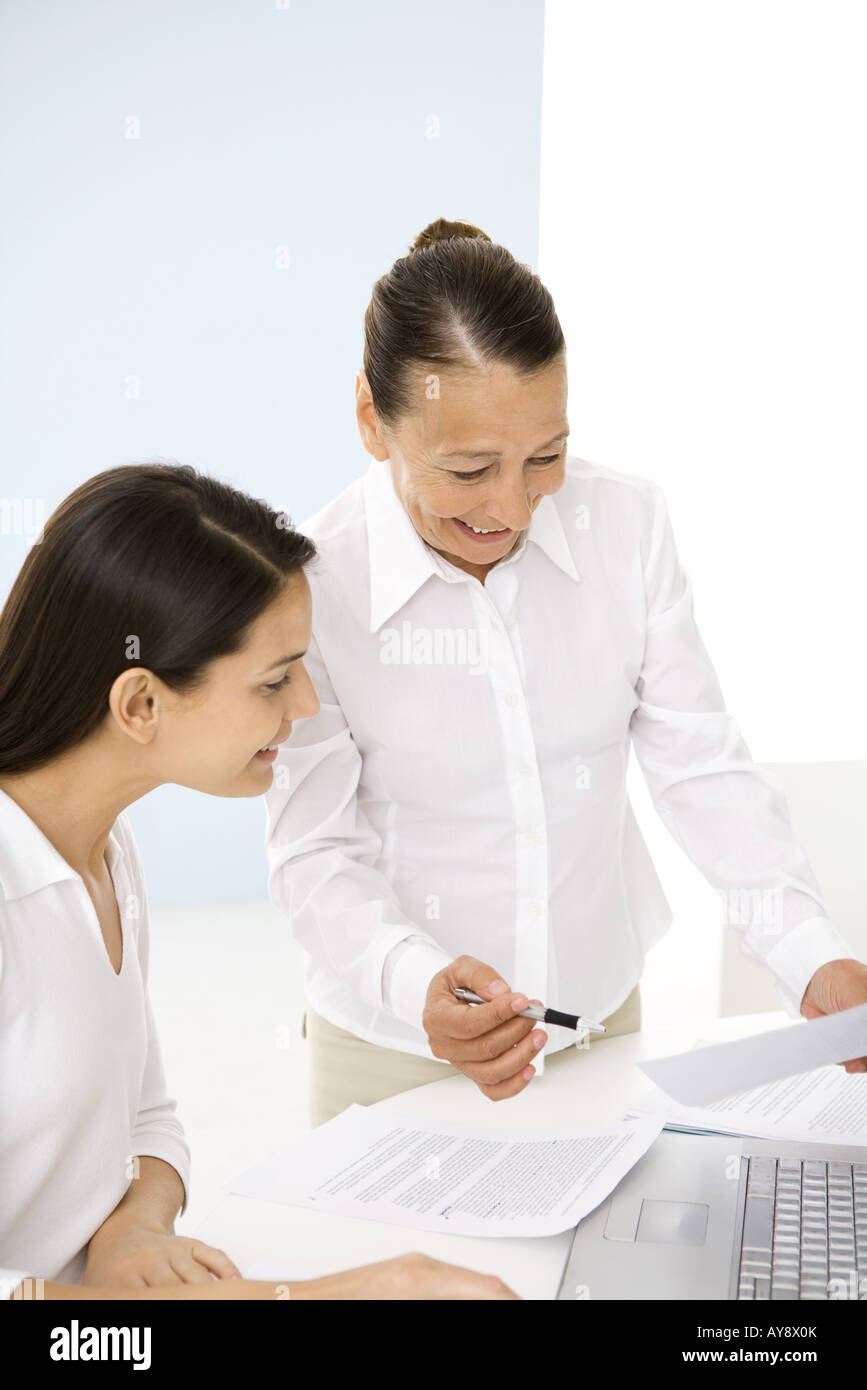 Senior woman working with younger colleague in office, smiling Stock Photo