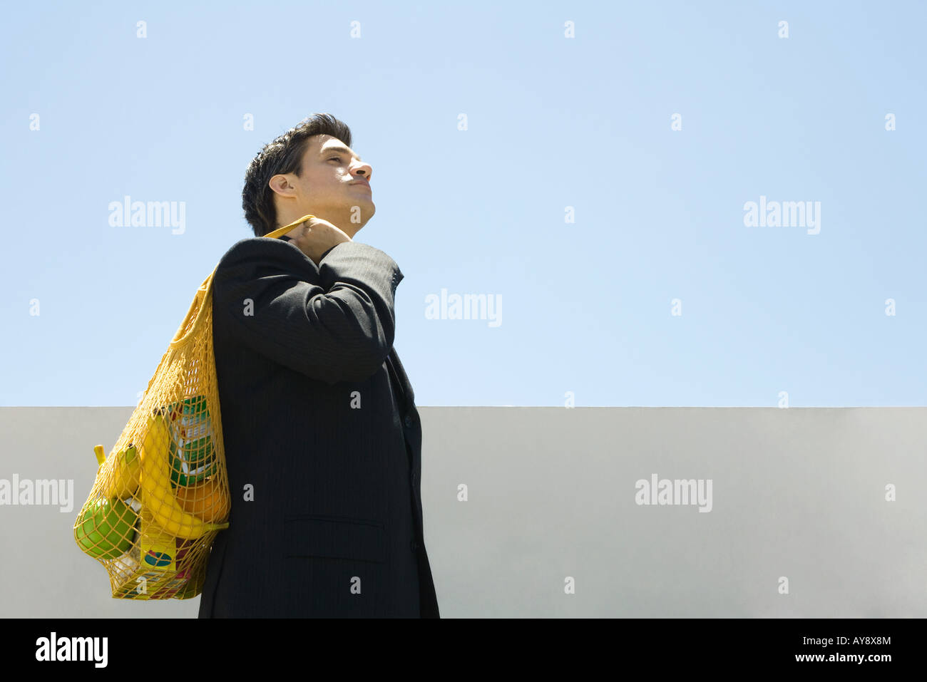 Businessman carrying groceries over shoulder Stock Photo