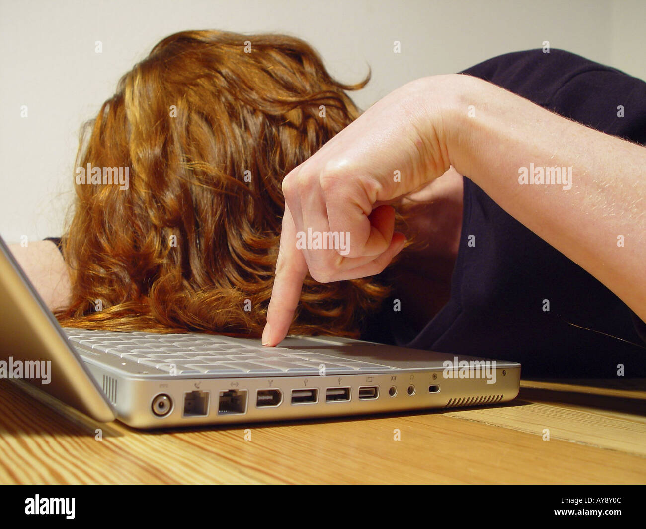 Eine Frau schlaeft auf der Tastatur eines Laptops ein Stock Photo