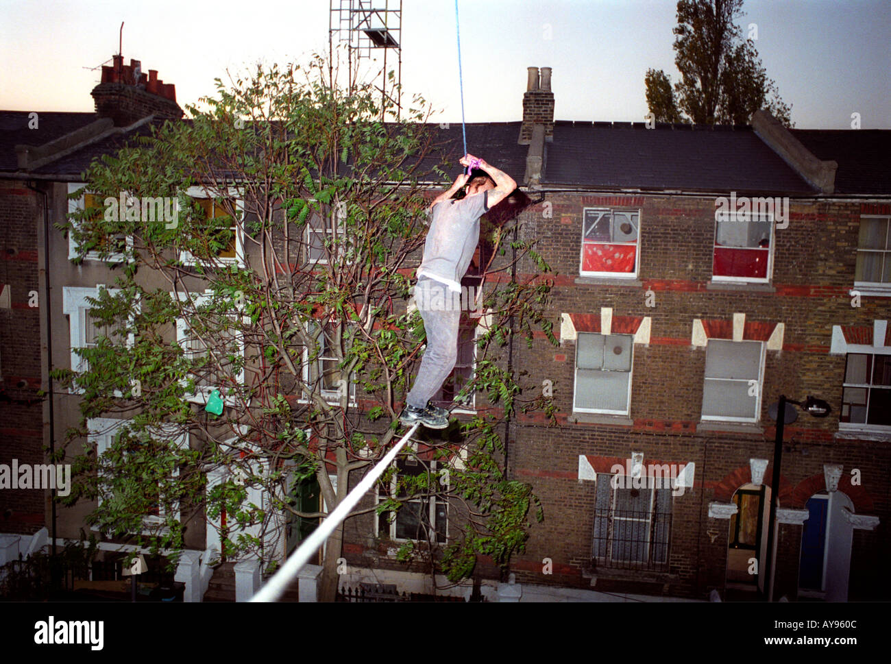 Protester on rope walkway between houses protesting imminent eviction at Saint Agnes Place squat in Kennington South London. Stock Photo